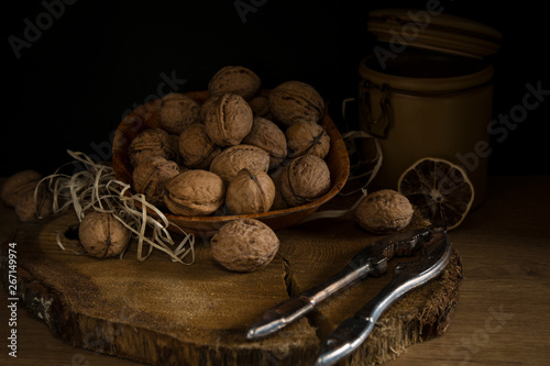 A brown plate with nuts on dark wood .Walnuts on dark background. Low-key image