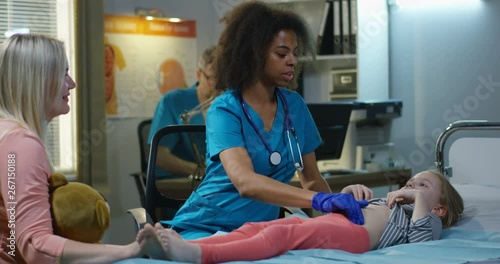 Female doctor examining girls abdomen photo