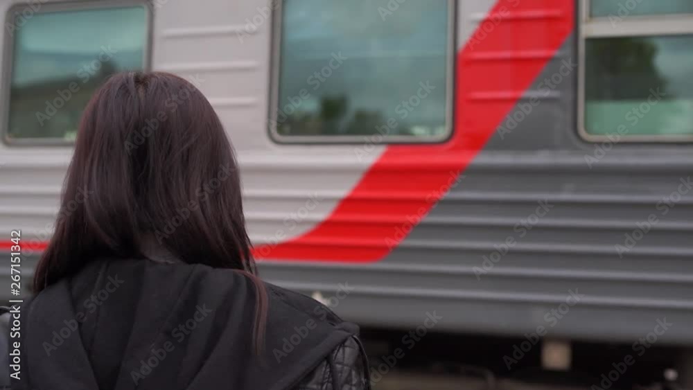 Young woman waiting for arrival of train. Side view unrecognizable young brunette female standing on platform and waiting for arrival of train Young woman waiting for arrival of train. Side view unrecognizable young brunette female standing on platform and waiting for arrival of train