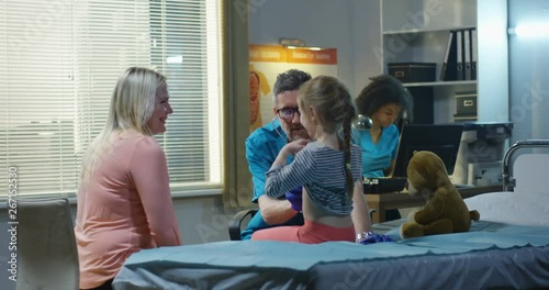 Friendly doctor examining teddy bear with stethoscope