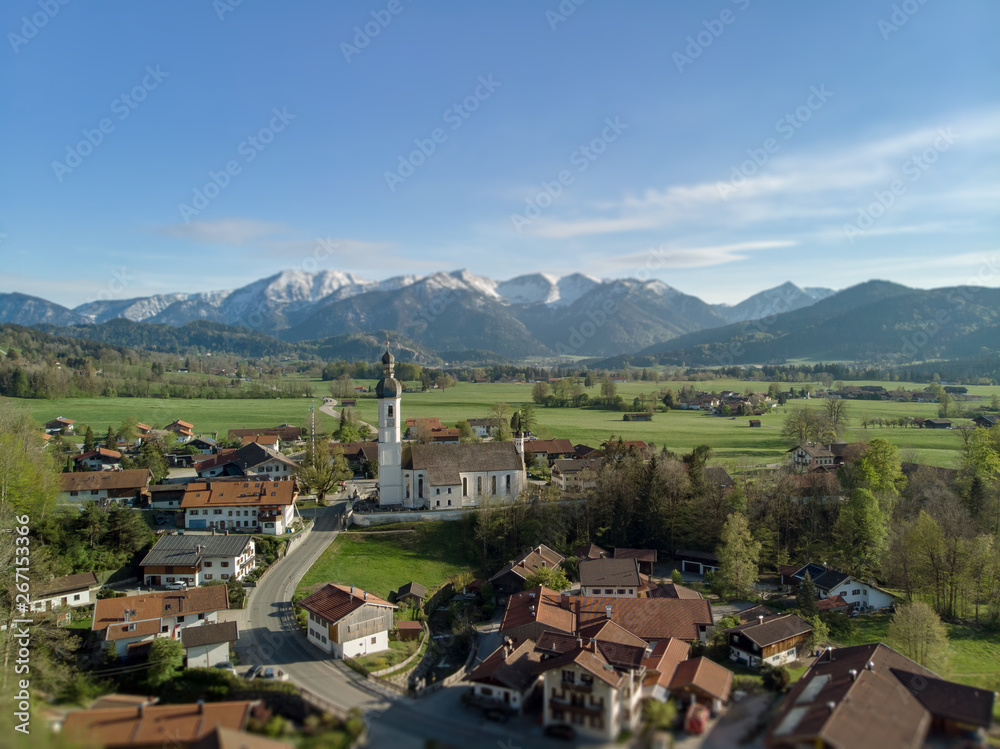 Aerial view of Bavarian village with catholic church and alps in the background