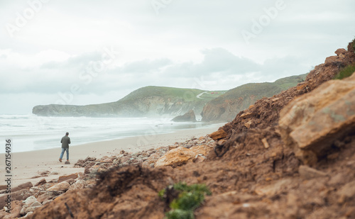 Man walking at beach in Cantabria, north of Spain