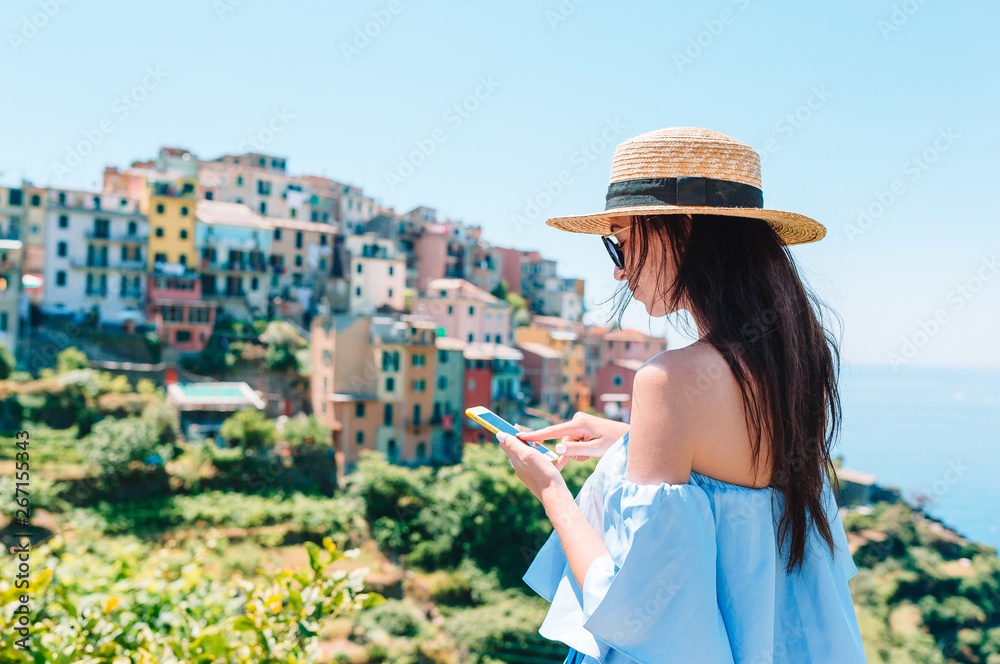 Young woman take a photo of beautiful view at old village in Cinque Terre, Liguria, Italy. European italian vacation.