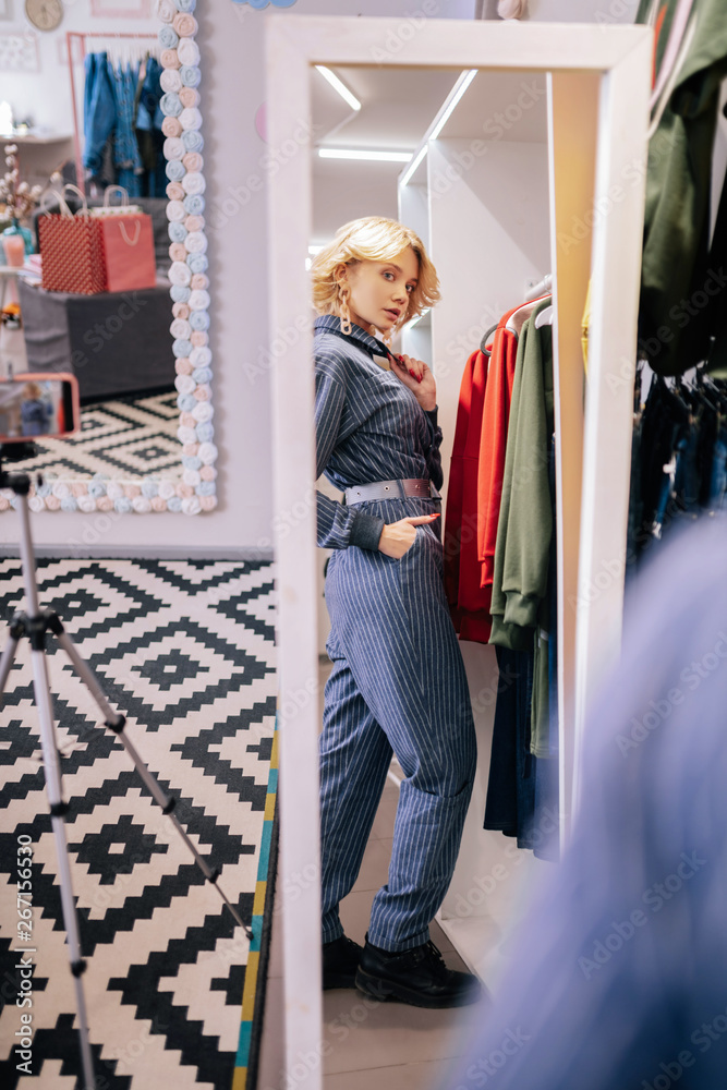 Fototapeta premium Woman looking into mirror after choosing stylish jumper suit