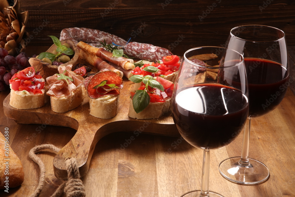 antipasto various appetizer. Cutting board with prosciutto, salami, cheese, bread and olives on dark wooden background