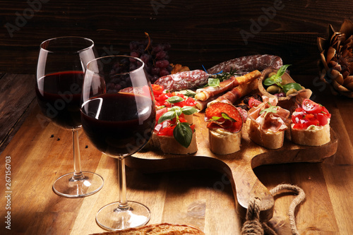 antipasto various appetizer. Cutting board with prosciutto, salami, cheese, bread and olives on dark wooden background