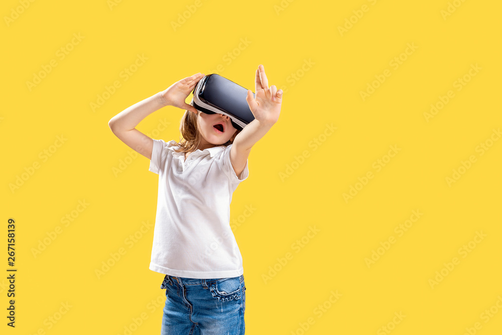 Girl 7 y.o. experiencing VR headset game on yellow background. Surprised emotions on her face.Child using a gaming gadget for virtual reality.Futuristic goggles at young age. Virtual technology Girl 7 y.o. experiencing VR headset game on yellow background. Surprised emotions on her face.Child using a gaming gadget for virtual reality.Futuristic goggles at young age. Virtual technology