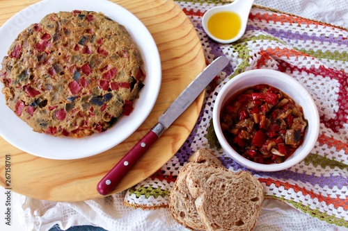 Tortilla de pisto sobre plato blanco y fondo madera y crochet