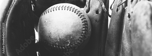 Close up of old vintage baseball in used worn leather glove, black and white sports banner.