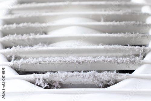 Extremely dirty and dusty white plastic ventilation air grille at home close up, harmful for health photo