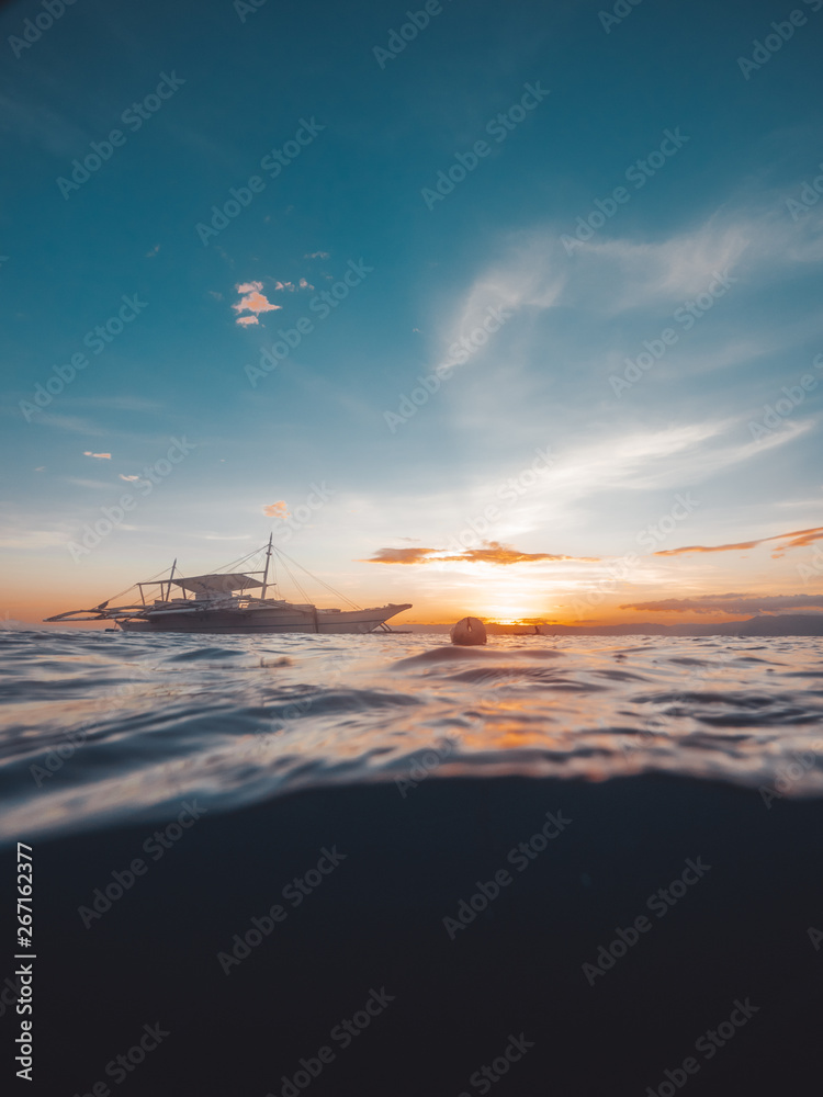 Yacht sailing in sea on colorful evening sky landscape waterline view. White sea boat floating on sea waves on blue and orange sky background while evening sunset.