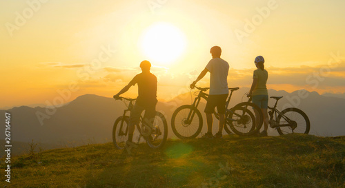 SILHOUETTE: Mountain bikers rest at the grassy mountaintop and observe sunrise.