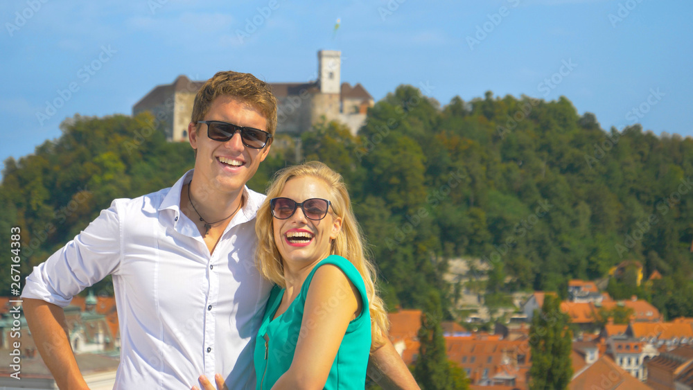 PORTRAIT: Happy woman poses with her boyfriend in front of the Ljubljana castle.