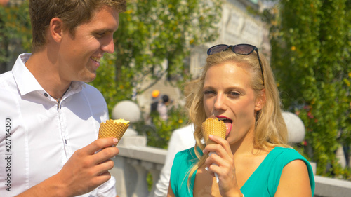 CLOSE UP: Young man looks at his girlfriend as they eat delicious ice cream.