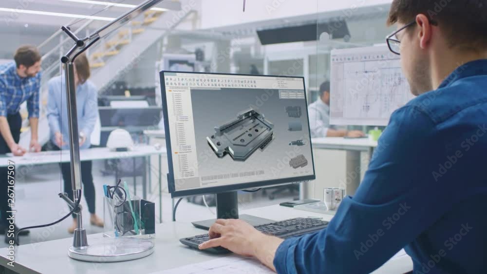 Engineer Working on Desktop Computer, Screen Showing CAD Software with 3D Component. In the Background Engineering Facility with Blueprints and Drawings with Industrial Design. Over the Shoulder Engineer Working on Desktop Computer, Screen Showing CAD Software with 3D Component. In the Background Engineering Facility with Blueprints and Drawings with Industrial Design. Over the Shoulder