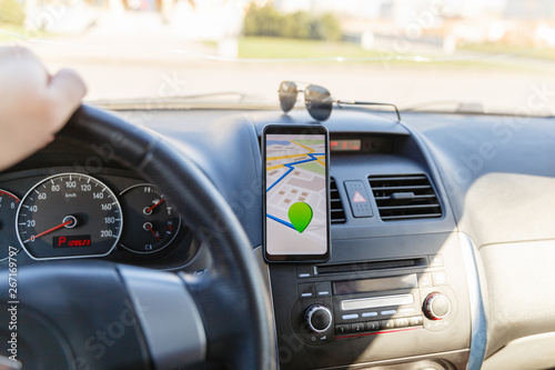Arrival or destination point on the map in the phone on the dashboard background. Black mobile phone with GPS map navigation is fixed in the installation. App map for traveling with route © korchemkin