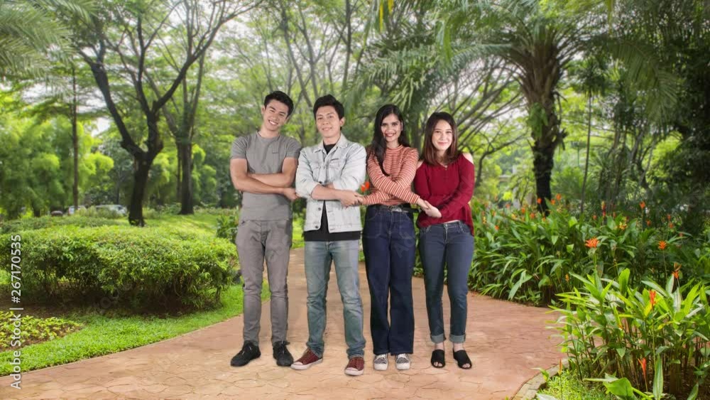 Group of young people smiling at the camera while holding hands in line at the park. Unity and teamwork concept. Shot in 4k resolution Group of young people smiling at the camera while holding hands in line at the park. Unity and teamwork concept. Shot in 4k resolution