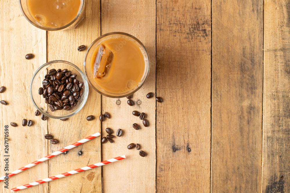 Flat lay. Cold coffee in transparent glasses with ice and straws, on a wooden background, cooling drink, refreshing, summer mood, with copy space Flat lay. Cold coffee in transparent glasses with ice and straws, on a wooden background, cooling drink, refreshing, summer mood, with copy space