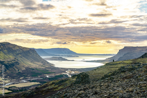 Sun covered valley in Hvalfjörður, Iceland during summer. Stacks of rocks and a river flowing through the landscape