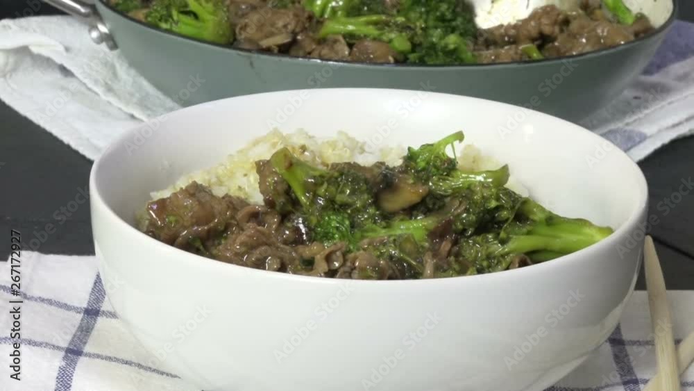 Spooning beef and broccoli into a bowl of rice, slow motion Spooning beef and broccoli into a bowl of rice, slow motion