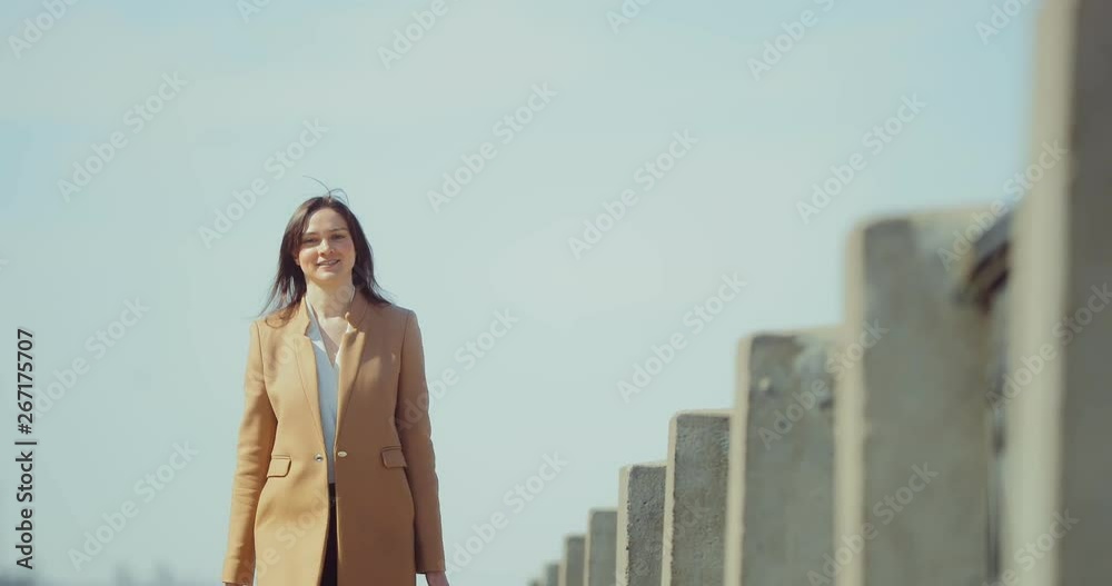 Happy girl walking down the street early in the morning. Young brunette woman walks along the path of the park. Portrait view. Happy girl walking down the street early in the morning. Young brunette woman walks along the path of the park. Portrait view.