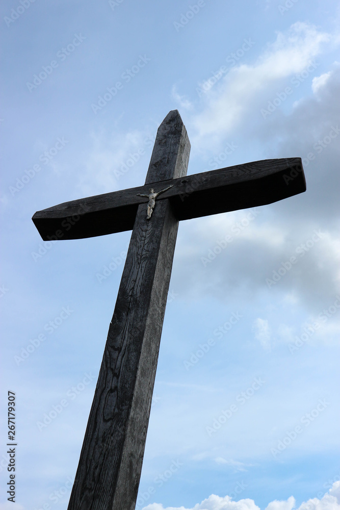 large wooden cross with figure of christ against blue sky