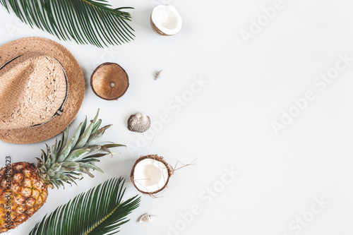Summer composition. Tropical palm leaves, hat, coconut, pineapple on pastel gray background. Summer concept. Flat lay, top view, copy space