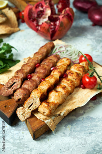 Plates of meat with barbecue and kebab, on gray background
