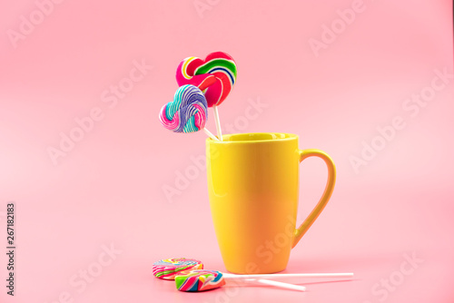 Multicolored lollipops in a container on a pink background