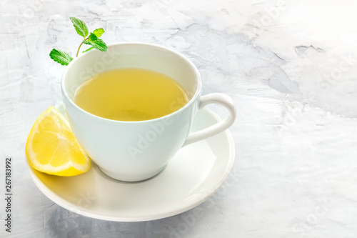 A cup of tea with a slice of lemon and mint leaves, with copy space