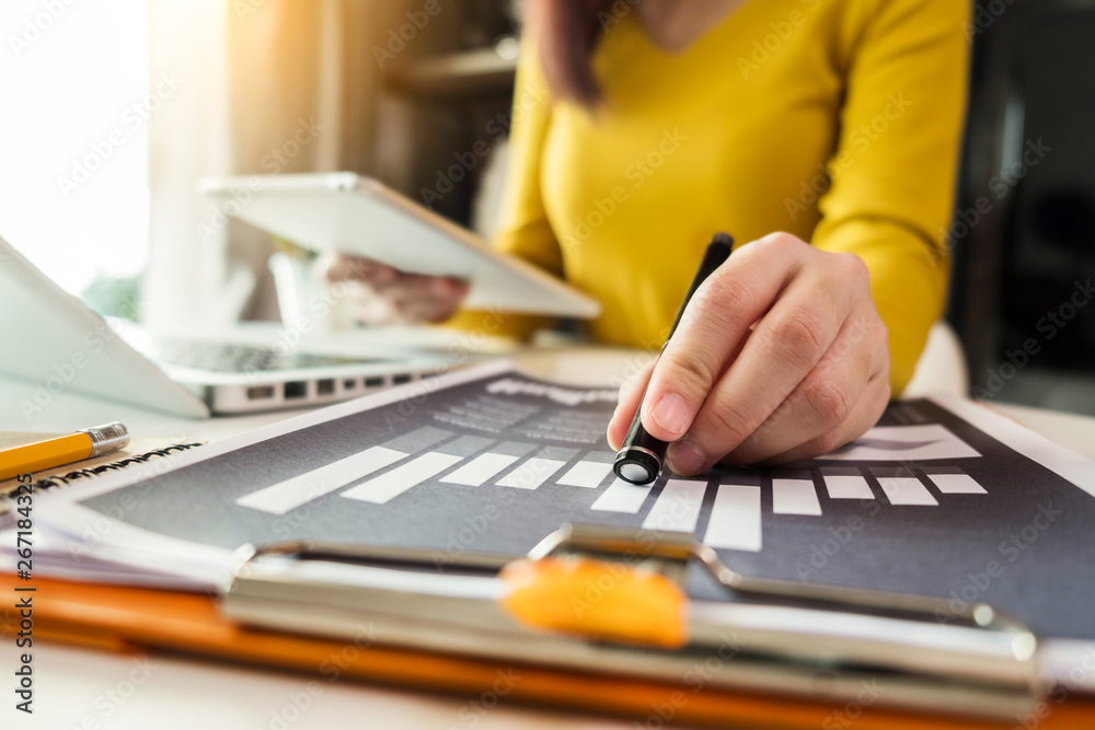 business documents on office desk with laptop and graph business diagram and Woman working at office. business documents on office desk with laptop and graph business diagram and Woman working at office.