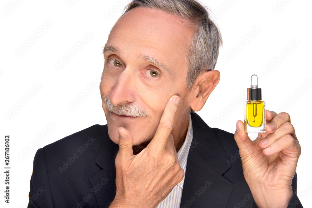 Smiling mature businessman in suit showing anti-aging lotion product , enjoying his perfect face skin, cheek, pimple, whelk, pustule, dry, oiled, problem skin concept, isolated on white background Smiling mature businessman in suit showing anti-aging lotion product , enjoying his perfect face skin, cheek, pimple, whelk, pustule, dry, oiled, problem skin concept, isolated on white background