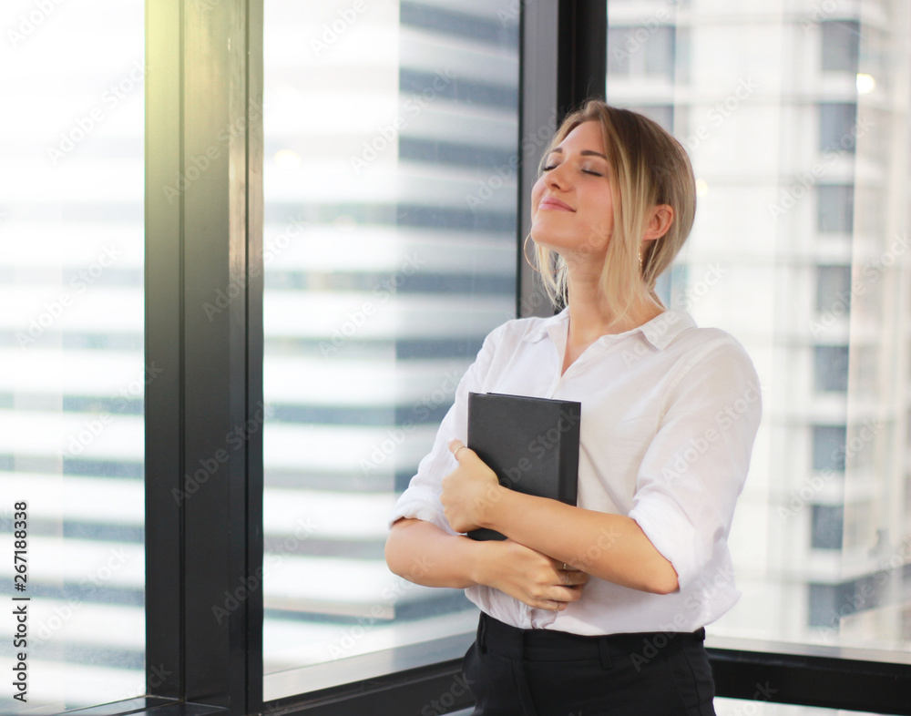 Portrait of a businesswoman holding notebook in modern office