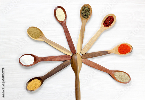 Assortment of spices in wooden spoons, white background
