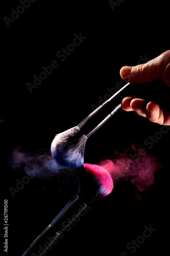 Splash of powder on a black background brushes for make up on a black background.