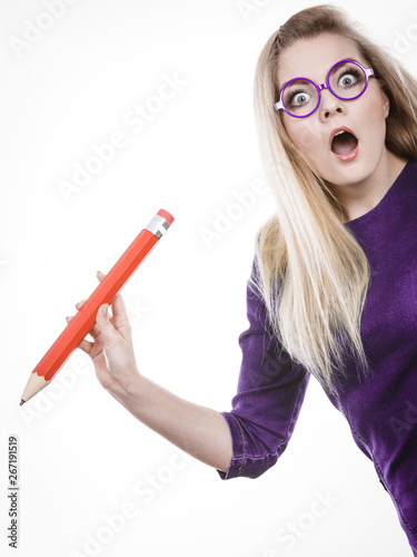 Shocked woman holds big pencil in hand