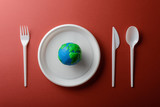 Serving table with Earth planet, plastic plate, spoon, fork and knife. Ecology Concept for Earth Hour, Earth Day, Ocean Day and other ECO dates.