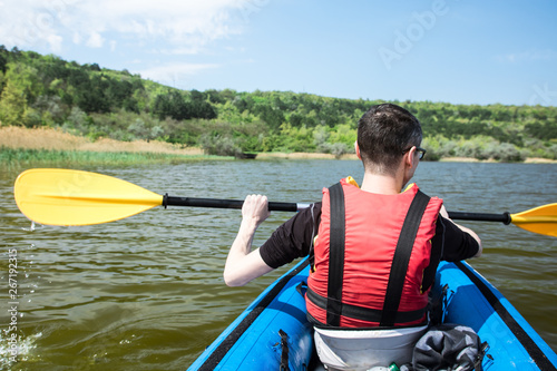 unrecognizable man in life vest kayaking on lake in a folding kayak
