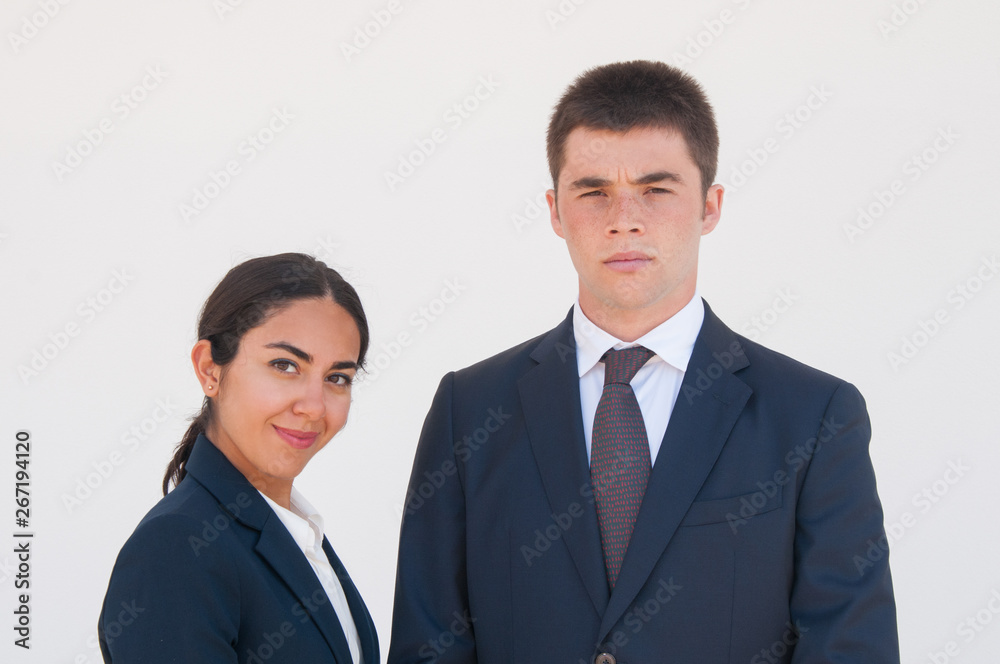 Joyful and serious business colleagues posing against white background. Portrait of pensive young man and cheerful woman in formal jackets. Successful workgroup concept Joyful and serious business colleagues posing against white background. Portrait of pensive young man and cheerful woman in formal jackets. Successful workgroup concept
