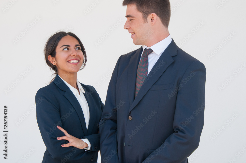Joyful colleagues chatting and joking. Young man and woman in formal suits smiling at each other and talking. United team concept Joyful colleagues chatting and joking. Young man and woman in formal suits smiling at each other and talking. United team concept