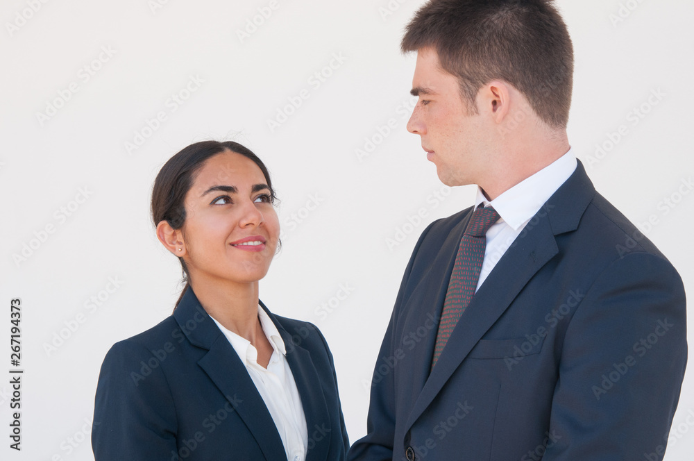 Positive coworkers discussing project. Young man and woman in formal suits smiling at each other and enjoying nice talk. Teamwork concept Positive coworkers discussing project. Young man and woman in formal suits smiling at each other and enjoying nice talk. Teamwork concept