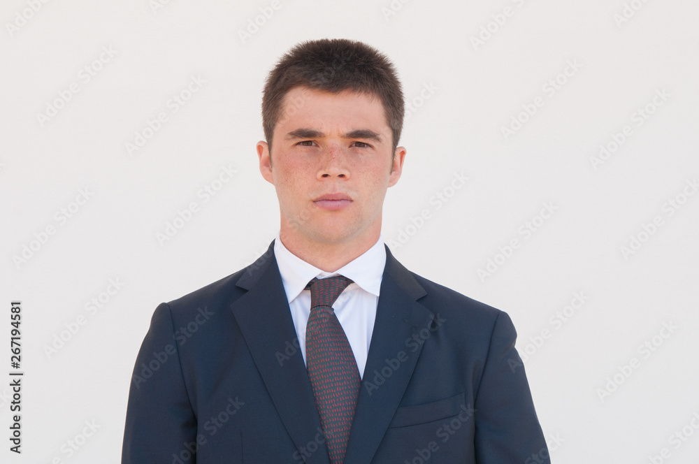 Serious man in formal jacket and tie standing for camera. Portrait of young businessman or business professional. Male business portrait concept Serious man in formal jacket and tie standing for camera. Portrait of young businessman or business professional. Male business portrait concept