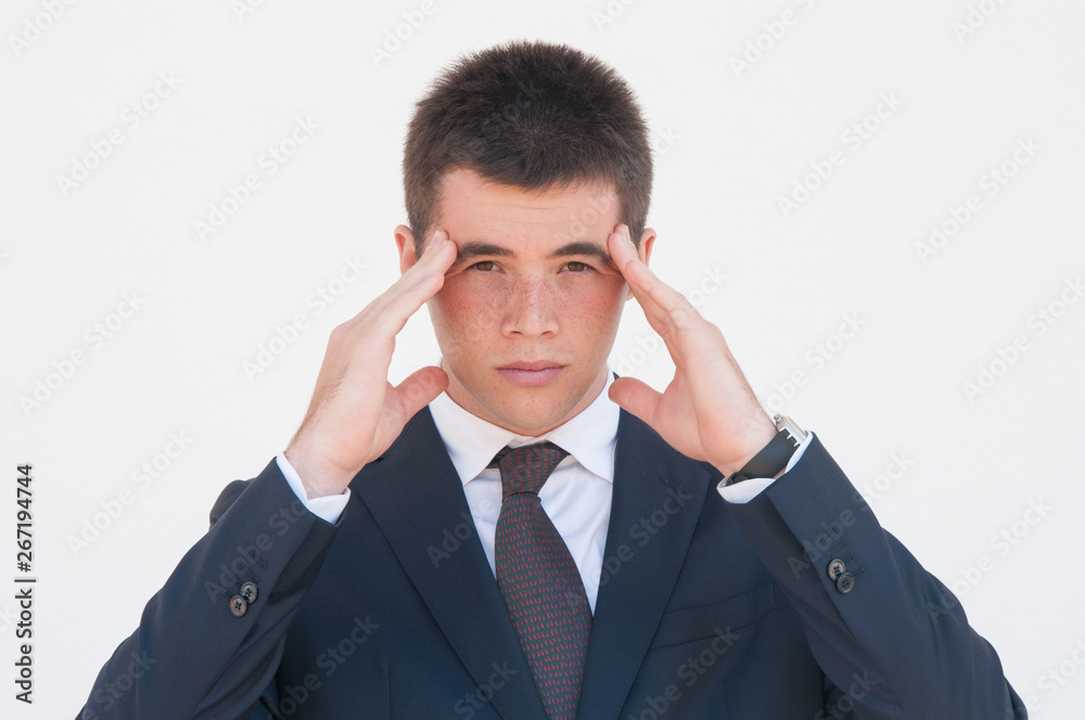 Tired pensive office employee suffering from head ache. Young man touching head and massaging temples. Headache concept Tired pensive office employee suffering from head ache. Young man touching head and massaging temples. Headache concept