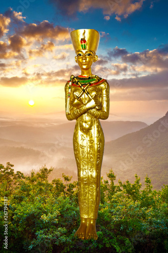 Nofretete, Statuette goldfarben vor schönem Hintergrund mit Sonnenaufgang, ägyptischer Pharaon und Göttin  photo