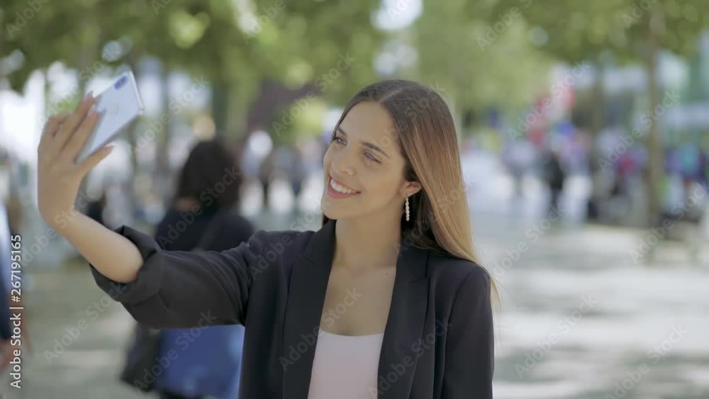 Attractive girl taking selfie with smartphone outdoor. Beautiful smiling young woman standing on street and taking pictures with mobile phone. Technology concept Attractive girl taking selfie with smartphone outdoor. Beautiful smiling young woman standing on street and taking pictures with mobile phone. Technology concept
