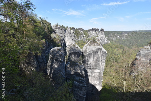 Big grey rocks with mountains and trees in background at Elbe Sandstone Mountains in beautiful Saxon Switzerland near Bohemian Switzerland in Germany