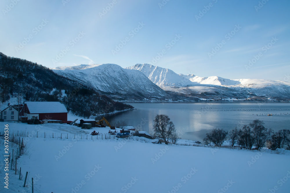 Coastline Norway, view over fish farm with late afternoon sun on mountains in background