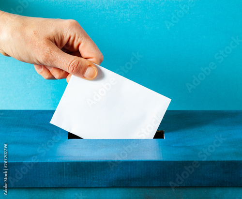 european Union parliament election concept - hand putting ballot in blue election box photo