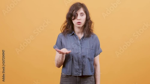 Beautiful young woman dissaproves and nagates a statement. Portrait of a young female over a yellow background. photo