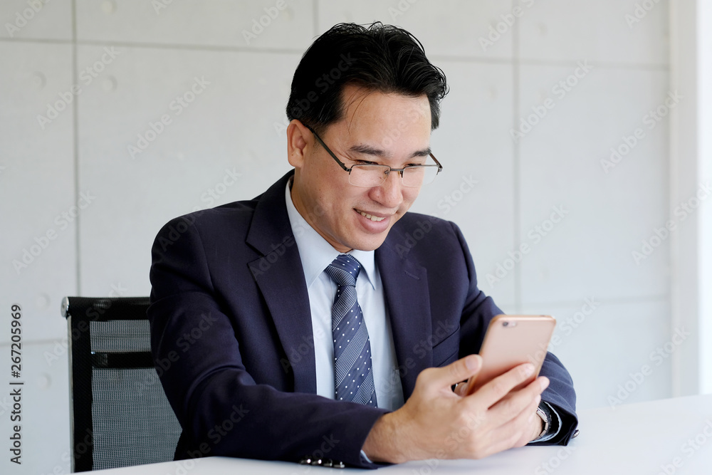 Asian businessman usiing smart phone at office background, business people on smart phone, business and technology Asian businessman usiing smart phone at office background, business people on smart phone, business and technology